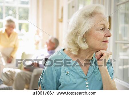 Stock Photo - Senior woman looking through window in nursing home. Fotosearch