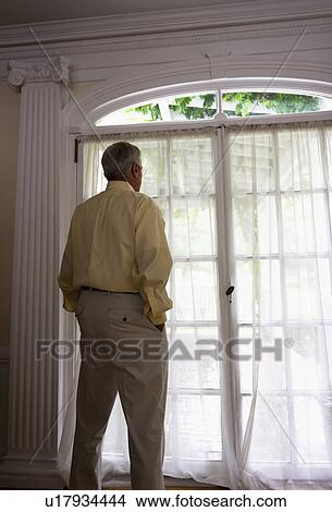 Senior woman looking through window View Large Photo Image Picture - Senior woman looking through window. Fotosearch