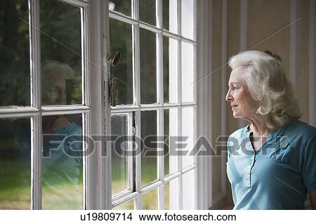 Senior woman looking through window View Large Photo Image Picture - Senior woman looking through window. Fotosearch