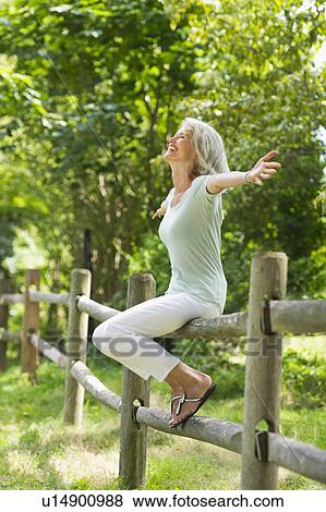 Senior woman sitting on fence View Large Photo Image Stock Photo - Senior woman sitting on fence. Fotosearch