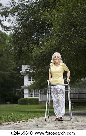 Stock Image - Senior woman walking with walker. Fotosearch