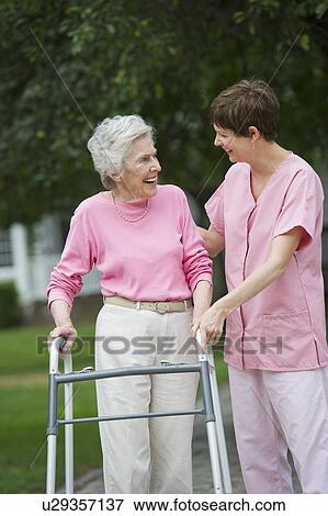Senior woman walking with walker with help of nursing assistant View Large Photo Image Stock Photo - Senior woman walking with walker with help of nursing assistant. Fotosearch