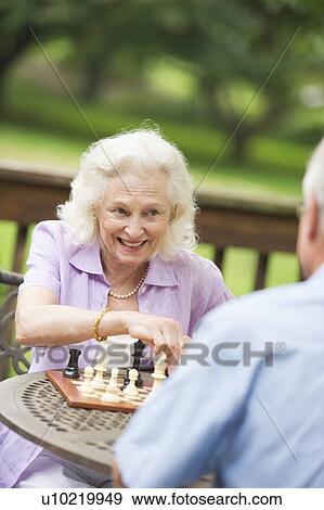 Stock Photo - Seniors playing chess on porch. Fotosearch