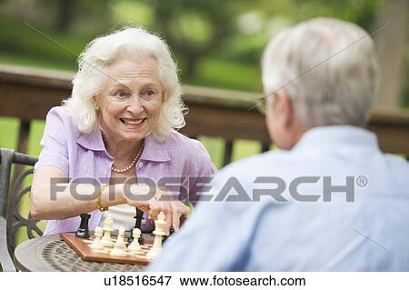 Stock Photo - Seniors playing chess on porch. Fotosearch
