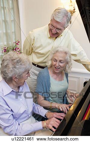 Stock Image - Seniors playing piano and singing. Fotosearch