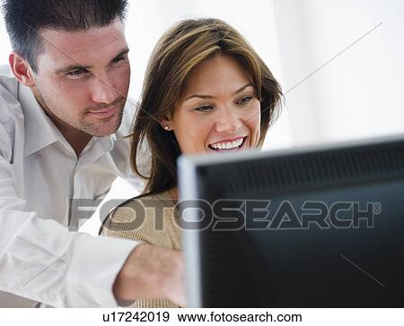 Smiling couple looking at monitor View Large Photo Image Stock Photo - Smiling couple looking at monitor. Fotosearch