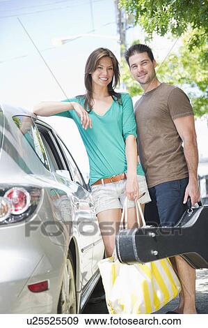 Smiling couple on vacations standing near car View Large Photo Image Stock Photo - Smiling couple on vacations standing near car. Fotosearch