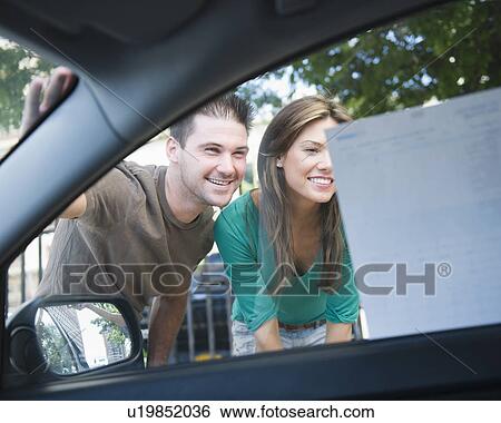 Smiling couple riding advertisement on car window View Large Photo Image Stock Photograph - Smiling couple riding advertisement on car window. Fotosearch