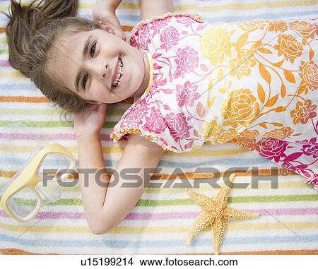 Picture - Smiling girl ( 6-7) lying on towel on vacations. Fotosearch