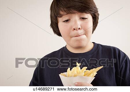 Studio portrait of boy (10-11) holding french fries View Large Photo Image Stock Image - Studio portrait of boy (10-11) holding french fries. Fotosearch