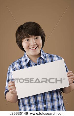 Stock Photo - Studio portrait of boy (10-11) holding blank sheet of paper. Fotosearch