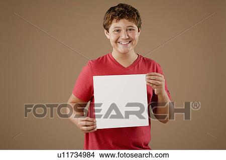 Studio portrait of boy (12-13) holding blank sheet of paper View Large Photo Image Picture - Studio portrait of boy (12-13) holding blank sheet of paper. Fotosearch