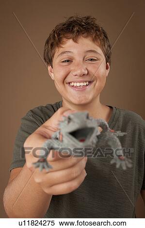 Stock Photography - Studio portrait of boy (12-13) holding plastic animal. Fotosearch