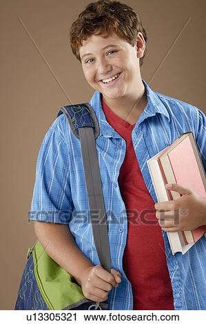 Stock Image - Studio portrait of boy (12-13) with backpack and books. Fotosearch