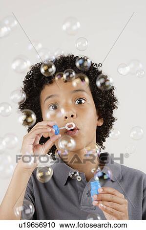 Studio portrait of boy (8-9) blowing bubbles View Large Photo Image Stock Image - Studio portrait of boy (8-9) blowing bubbles. Fotosearch