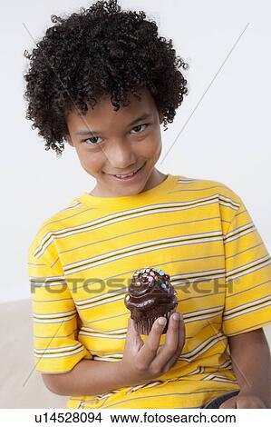 Studio portrait of boy (8-9) holding muffin View Large Photo Image Picture - Studio portrait of boy (8-9) holding muffin. Fotosearch