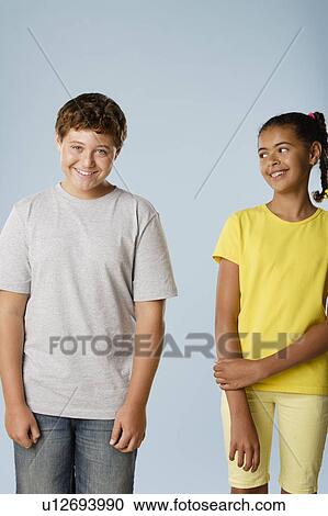 Stock Image - Studio portrait of boy and girl (10-11, 12-13). Fotosearch