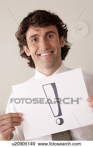 Stock Photo - Studio portrait of businessman holding sheet of paper with exclamation mark. Fotosearch