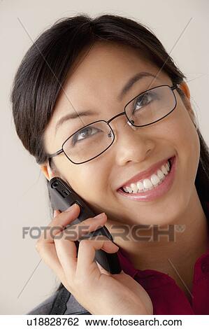 Stock Image - Studio portrait of businesswoman talking on cell phone. Fotosearch
