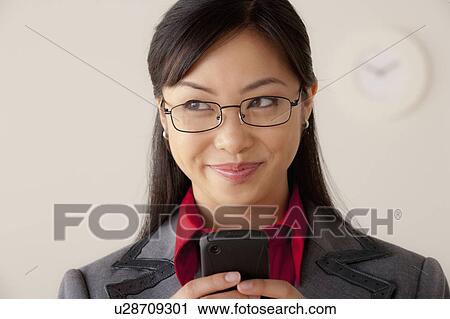 Stock Image - Studio portrait of businesswoman text-messaging. Fotosearch