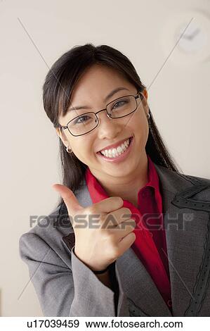 Stock Photo - Studio portrait of businesswoman showing thumbs-up. Fotosearch