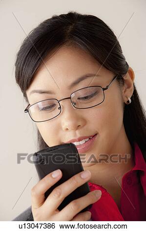 Stock Photograph - Studio portrait of businesswoman text-messaging. Fotosearch