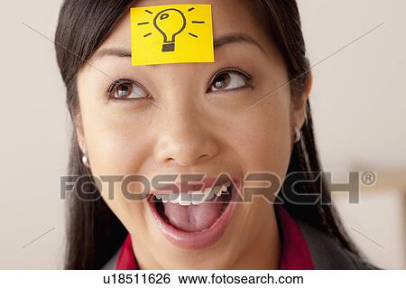 Stock Photograph - Studio portrait of businesswoman with adhesive note on forehead. Fotosearch