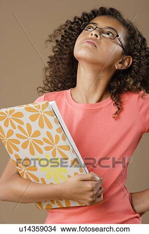 Studio portrait of girl (10-11) holding book View Large Photo Image Picture - Studio portrait of girl (10-11) holding book. Fotosearch