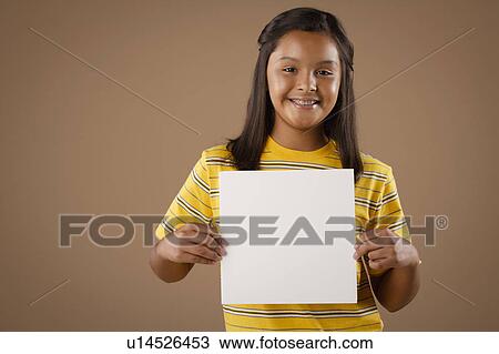 Stock Image - Studio portrait of girl (10-11) holding blank sheet of paper. Fotosearch