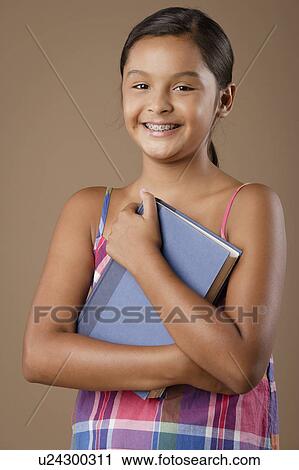 Studio portrait of girl (10-11) holding book View Large Photo Image Stock Image - Studio portrait of girl (10-11) holding book. Fotosearch