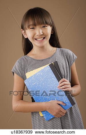 Studio portrait of girl (10-11) holding book View Large Photo Image Stock Photo - Studio portrait of girl (10-11) holding book. Fotosearch