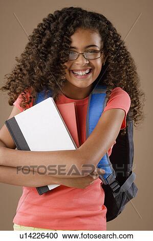 Stock Image - Studio portrait of girl (10-11) with backpack and books. Fotosearch