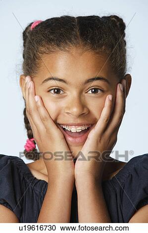 Stock Image - Studio portrait of girl (10-11) with head in hands. Fotosearch