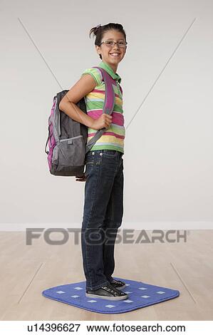 Stock Photo - Studio portrait of girl (8-9) carrying backpack. Fotosearch