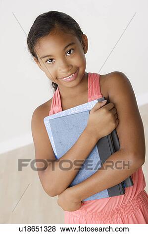 Studio portrait of girl (8-9) holding books View Large Photo Image Stock Photo - Studio portrait of girl (8-9) holding books. Fotosearch