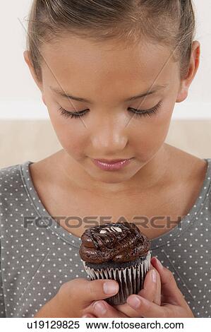 Stock Photography - Studio portrait of girl (8-9) holding cake. Fotosearch