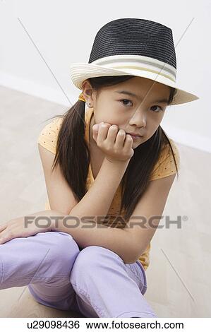 Stock Photograph - Studio portrait of girl (8-9) wearing hat. Fotosearch