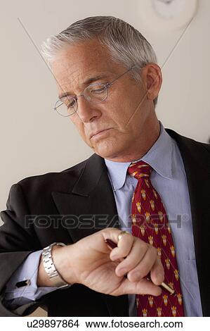 Studio portrait of senior businessman checking time View Large Photo Image Picture - Studio portrait of senior businessman checking time. Fotosearch