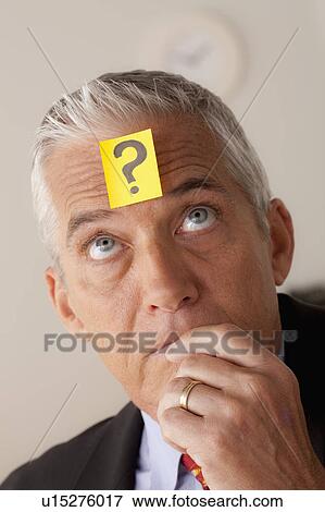 Stock Photo - Studio portrait of senior businessman with adhesive note on forehead. Fotosearch