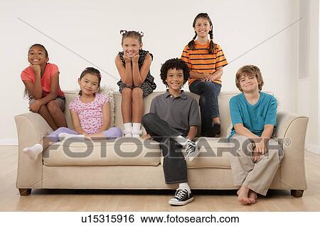 Stock Photograph - Studio portrait of six children (8-9) sitting on sofa. Fotosearch