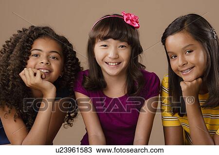 Stock Image - Studio portrait of three girls (10-11). Fotosearch