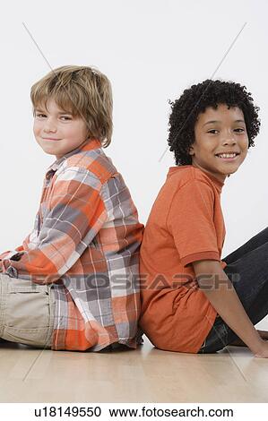 Studio portrait of two boys (8-9) sitting back to back View Large Photo Image Stock Image - Studio portrait of two boys (8-9) sitting back to back. Fotosearch