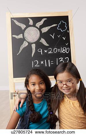 Picture - Studio portrait of two girls (8-9) in front of blackboard. Fotosearch