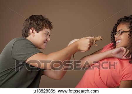 Stock Photography - Studio shot of boy (12-13) teasing girl (10-11). Fotosearch
