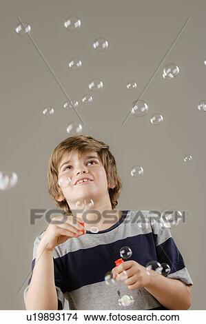 Picture - Studio shot of boy (8-9) blowing bubbles. Fotosearch