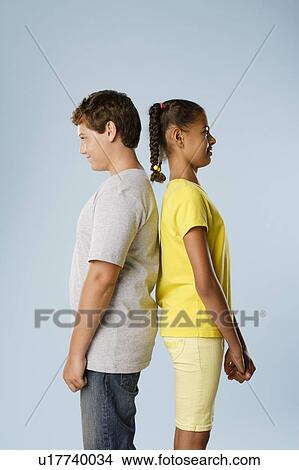 Studio shot of boy and girl (10-11, 12-13) standing back to back View Large Photo Image Picture - Studio shot of boy and girl (10-11, 12-13) standing back to back. Fotosearch