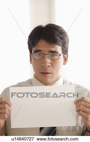 Stock Photo - Studio shot of business man holding blank paper. Fotosearch