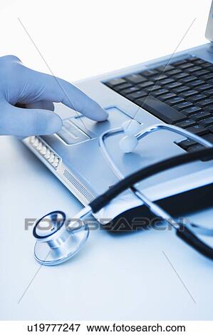 Stock Photo - Studio shot of doctor's hand touching laptop. Fotosearch