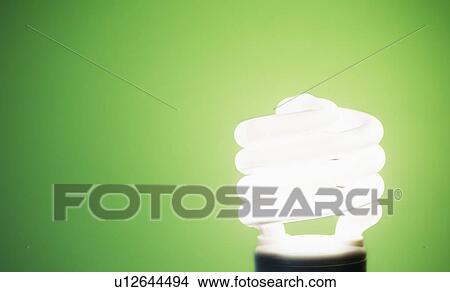 Picture - Studio shot of energy efficient lightbulb on green background. Fotosearch