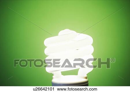 Stock Image - Studio shot of energy efficient lightbulb on green background. Fotosearch